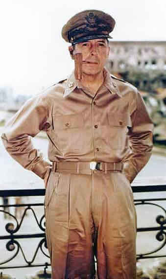 Photographic image of General MacArthur dressed in military khakis with a pipe in his mouth.